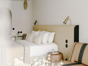 a bedroom with a bed with white pillows and a table at Hôtel & Spa Belle Plage in Cannes