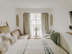 a bedroom with a bed and a couch and a window at Hôtel & Spa Belle Plage in Cannes