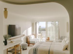 a white bedroom with a bed and a window at Hôtel & Spa Belle Plage in Cannes