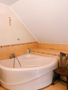 a large bath tub in a room with a chair at Spacious family house in the city centre in Pāvilosta