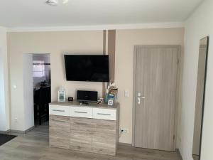 a living room with a tv and a dresser with a door at Ferienwohnung Blume in Schwielowsee