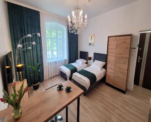 a bedroom with two beds and a table and a chandelier at GOOD DAY APARTMENT centrum Katowice in Katowice