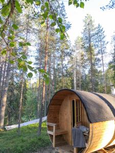 Cabaña de madera pequeña con techo de paja en un bosque en AuroraHut Pytkyn Iglu, en Syöte