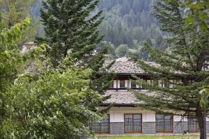 a house in the mountains with trees in the foreground at Gressoney Saint-Jean apartments by Halldis in Gressoney-Saint-Jean