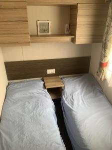 um quarto com uma cama e uma secretária e uma cama sidx sidx em CLJP Caravan Thorpe Park Cleethorpes Free WI-FI em Cleethorpes