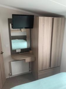 a bedroom with a bed and a television on a wall at CLJP Caravan Thorpe Park Cleethorpes Free WI-FI in Cleethorpes