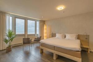 a bedroom with a bed and a large window at Hotel de Baak Seaside in Noordwijk aan Zee