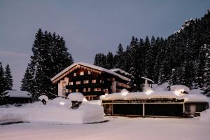 a building covered in snow in front of trees at Alpenhotel Heimspitze in Gargellen