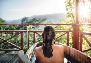 a woman sitting on a deck looking out at the mountains at Relais & Chateaux Hotel Castel Fragsburg in Merano