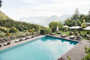 a swimming pool with chairs and mountains in the background at Relais & Chateaux Hotel Castel Fragsburg in Merano