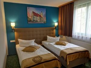 two beds in a hotel room with blue walls at ACRON Hotel Wittenberg in Lutherstadt Wittenberg