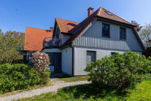 a white house with an orange roof and some bushes at Strandhaus Wustrow - Wohnung 4 in Wustrow