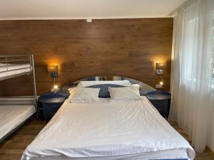 a bedroom with a large white bed with a wooden wall at CASA TARANEASCA in Baile Felix