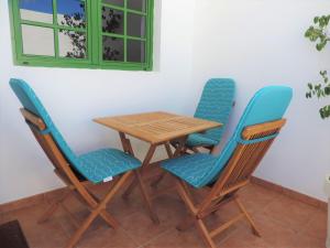 a wooden table and four chairs with blue seats at CASA ANGELINA in Playa Quemada