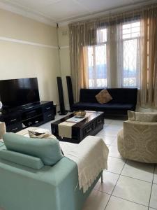 a living room with a couch and a tv at Fj's place in Durban