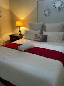 a large white bed with a red blanket on it at Fj's place in Durban