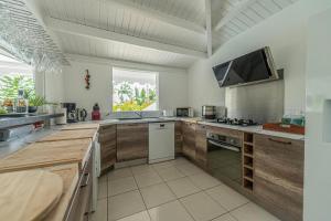 a large kitchen with wooden cabinets and a tv at Villa La Belle Creole in Saint-François
