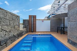 - une piscine dans une villa avec une table et un parasol dans l'établissement 3BR Home - Private Heated Pool - Parking, à Playa Blanca