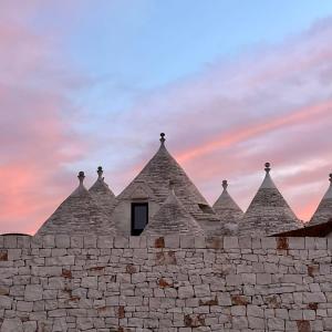 an old stone building with a sunset in the background at Quei Trulli Divini in Martina Franca