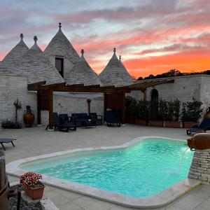 a swimming pool in front of a house with a sunset at Quei Trulli Divini in Martina Franca
