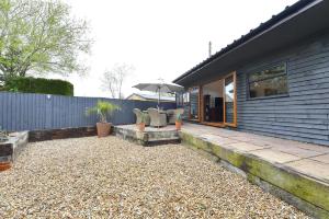 a house with a patio with chairs and an umbrella at Gorgeous 3BD Cottage in the Heart of Guildford in Guildford