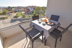 a table with two chairs and a plate of food on a balcony at Luxury apartment Punta with sea view and swimming pool in Premantura