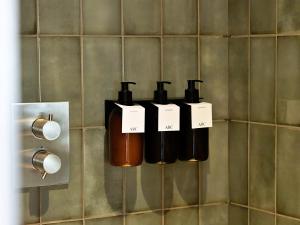 three bottles of soap are hanging on a wall at Finest Retreats - ARC Painswick in Painswick