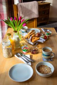 a wooden table with plates of food and flowers on it at Kirkaig Lodge in Lochinver