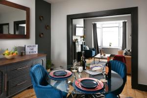 a dining room with a glass table and blue chairs at Sutton House by Pureserviced in Plymouth