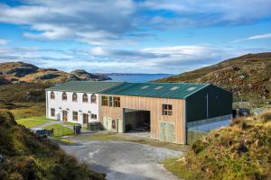 a large white building with a green roof on a hill at Kirkaig Lodge in Lochinver