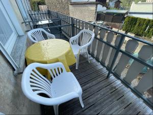 three white chairs and a yellow table on a balcony at Relaxen am Ring Fewo 2 in Wimbach