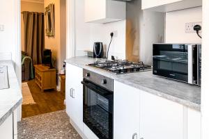 uma cozinha branca com um fogão e um micro-ondas em The Knavesmire - Quaint Victorian Home With Free Parking em York