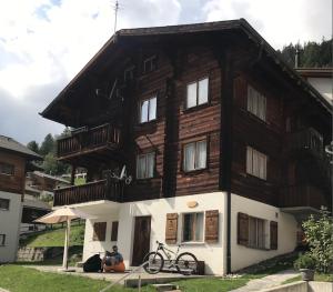 a house with two people sitting in front of it at Ferienwohnung im Chalet Boubou in Wiler