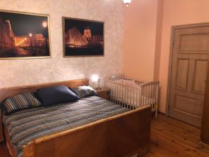 1 dormitorio con 1 cama y 1 cuna y cuadros en la pared en Classical large apartment on Alberta street, FREE PARKING, en Riga