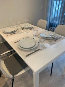 レイキャビクにあるLaugavegur Apartmentの白いテーブル(皿、ワイングラス付)