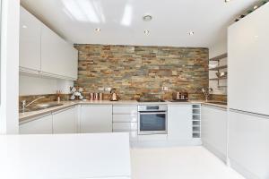 a kitchen with white cabinets and a brick wall at High Level - Properties Unique in Gateshead