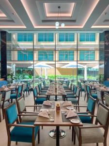 a restaurant with tables and chairs and a large window at Grand Millennium Al Seef Basra in Al Başrah