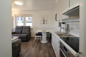 eine Küche und ein Wohnzimmer mit einem Sofa und einem Tisch in der Unterkunft App.8 Seeblick in Hörnum