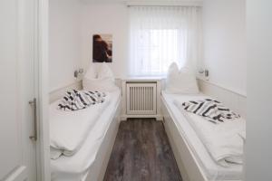 2 weiße Betten in einem Zimmer mit Fenster in der Unterkunft App.8 Seeblick in Hörnum