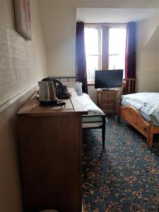 a hotel room with a desk with a bed and a television at Cedar Villa Guest House in Inverness