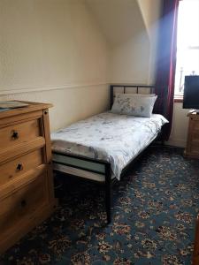 a small bedroom with a bed and a dresser at Cedar Villa Guest House in Inverness