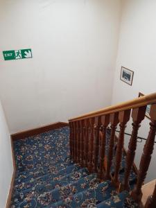 eine Treppe mit blauem Teppich und ein Schild an der Wand in der Unterkunft Cedar Villa Guest House in Inverness