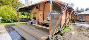 Luxe Safaritent Friesland في خراو: منزل به شرفة خشبية مع مقعد عليه