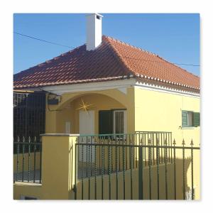 een geel huis met een hek en een dak bij Hostel Zabava in Odivelas