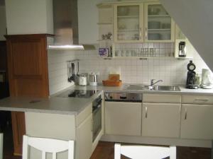 eine Küche mit weißen Schränken, einer Spüle und einer Theke in der Unterkunft Ferienwohnung Störmann in Timmendorfer Strand