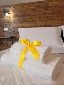 un mucchio di asciugamani con un fiocco giallo su un letto di Antonella's Home a Cavallino-Treporti