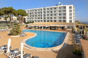 a hotel with a pool and chairs and a building at RVHotels Nieves Mar in L'Escala