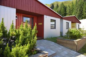 un edificio rojo y blanco con algunas plantas delante de él en Klausturhof Guesthouse en Kirkjubæjarklaustur