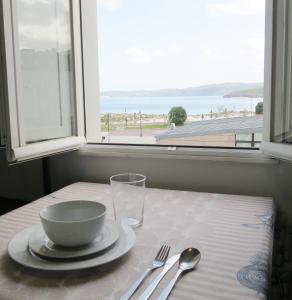 a table with a bowl and a plate on a table with a window at Piso Virgen del mar in Laxe