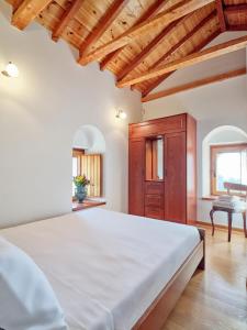 sypialnia z dużym białym łóżkiem i drewnianym sufitem w obiekcie Petreas Castle w mieście Kardamyli